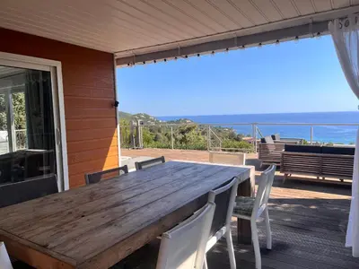 a wooden table and chairs on the porch of a house at VILLA GIOIA -Vue mer- proche plage de Favone in Conca