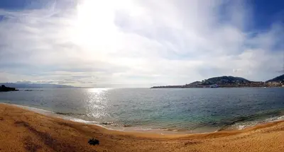 a beach with the sun shining on the water at Sudio bord de mer Ajaccio in Ajaccio