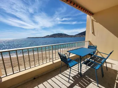 a balcony with a table and chairs and the beach at Sudio bord de mer Ajaccio in Ajaccio
