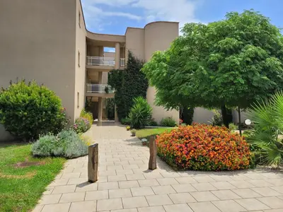 a building with a flower garden in front of it at Appartement T2 Bord de Mer - Maria Beach in Santa-Lucia-di-Moriani