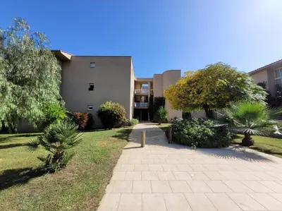 a building with a walkway in front of a yard at Appartement T2 Bord de Mer - Maria Beach in Santa-Lucia-di-Moriani