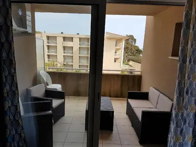 a balcony with couches and a view of a building at Appartement T2 Bord de Mer - Maria Beach in Santa-Lucia-di-Moriani