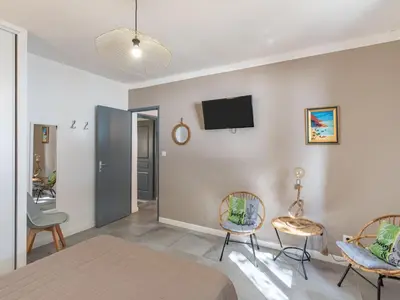 a bedroom with a bed and two chairs and a tv on the wall at Holiday Home Polpu by Interhome in Sari Solenzara