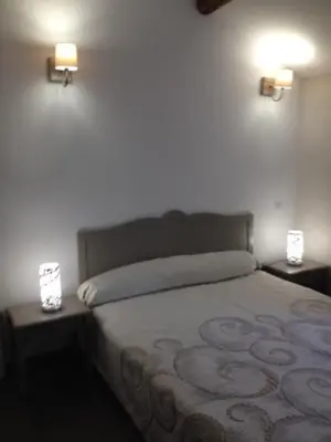 a bedroom with a bed with two lights on the wall at Casa Natalina de caractère entièrement rénovée classée 4 étoiles in Feliceto