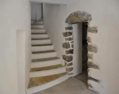 a staircase in a house with a stone wall at Casa Natalina de caractère entièrement rénovée classée 4 étoiles in Feliceto