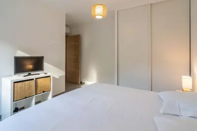 a bedroom with a white bed and a tv at Fronte di Mare - deux pièces en bord de mer in Propriano