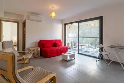 a living room with a red couch and a table at Fronte di Mare - deux pièces en bord de mer in Propriano