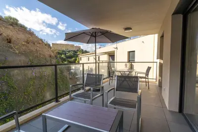 a balcony with a table and chairs and an umbrella at Fronte di Mare - deux pièces en bord de mer in Propriano
