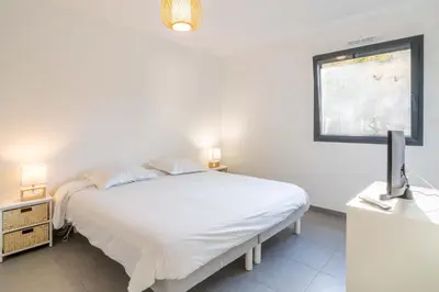 a white bedroom with a bed and a window at Fronte di Mare - deux pièces en bord de mer in Propriano
