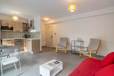 a living room with a red couch and a kitchen at Fronte di Mare - deux pièces en bord de mer in Propriano