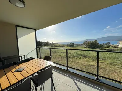 a room with a table and a balcony with a view at BEL'ORIZONTE Proche centre ville et plage, vue mer in Propriano