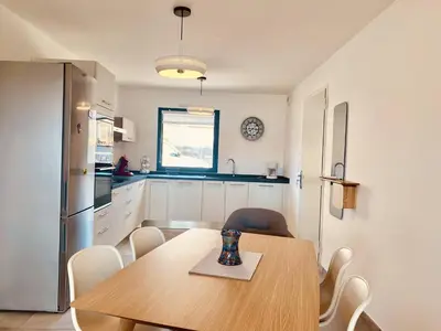 a kitchen with a wooden table and white cabinets at BEL'ORIZONTE Proche centre ville et plage, vue mer in Propriano