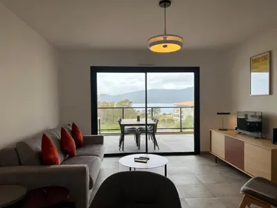 a living room with a couch and a table at BEL'ORIZONTE Proche centre ville et plage, vue mer in Propriano