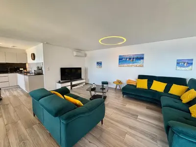 a living room with two green couches and a kitchen at Fronte di Mare - Grand confort vue mer in Propriano