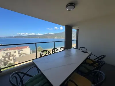 a dining room with a table and chairs and a large window at Fronte di Mare - Grand confort vue mer in Propriano