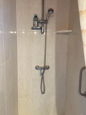 a shower with a shower head in a bathroom at Charmant studio avec piscine . in Afa