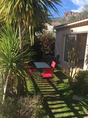 two red chairs and a table in a garden at Charmant studio avec piscine . in Afa