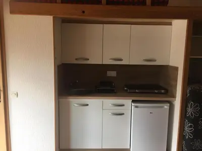 a kitchen with white cabinets and a sink at Charmant studio avec piscine . in Afa