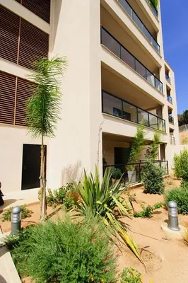 a building with a palm tree in front of it at T2 PORTICCIO AGOSTA PLAGE 100M DE LA PLAGE in Porticcio