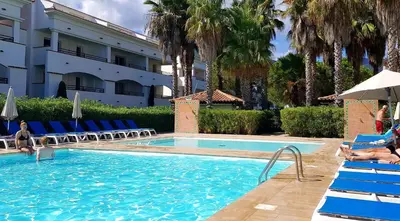 a swimming pool with palm trees and a hotel at Evasion Corse Direct mer Piscine Terrasse in Moriani Plage