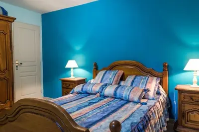 a blue bedroom with a bed and two night stands at Appartement dans maison chaleureuse in Olmeto