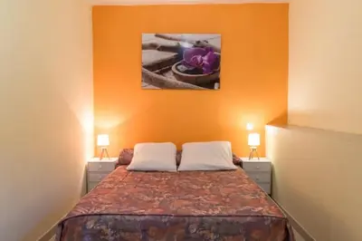 a bedroom with a bed with an orange wall at Appartement dans maison chaleureuse in Olmeto