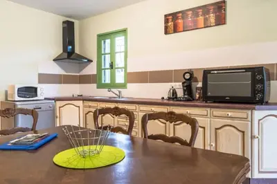 a kitchen with a table with a microwave and a television at Appartement dans maison chaleureuse in Olmeto