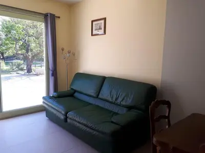 a green couch in a living room with a window at Appartement dans maison chaleureuse in Olmeto