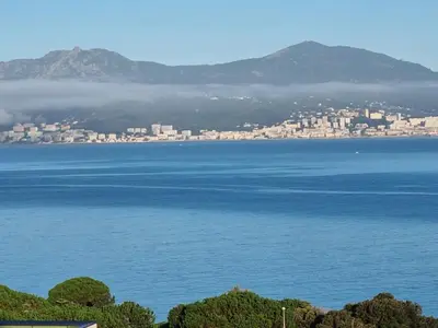 a large body of water with a city in the background at Superbe appartement T3 face mer baie Ajaccio in Pietrosella