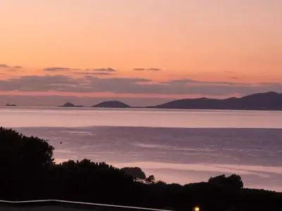 a sunset over the water with mountains in the background at Superbe appartement T3 face mer baie Ajaccio in Pietrosella