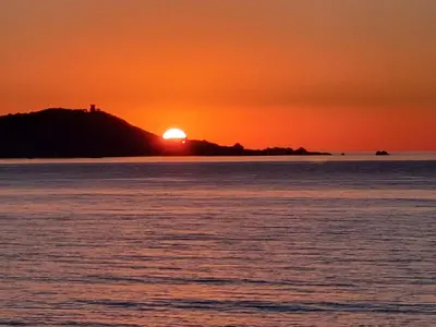 a sunset over a body of water with the sun setting at Superbe appartement T3 face mer baie Ajaccio in Pietrosella