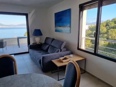 a living room with a couch and a table at Superbe appartement T3 face mer baie Ajaccio in Pietrosella
