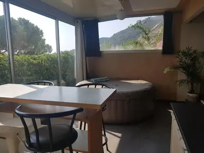 a room with a bed and a table and chairs at JACUZZI AJACCIO ENTRE MER ET MONTAGNE 200m DES PLUS BELLES PLAGES in Ajaccio