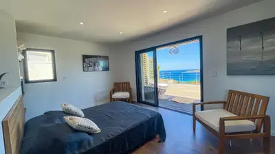 a bedroom with a bed and a view of the ocean at Villa Caramontinu in Sainte-Lucie de Porto-Vecchio