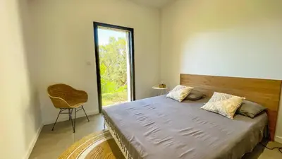 a bedroom with a bed with a window and a chair at Villa Caramontinu in Sainte-Lucie de Porto-Vecchio