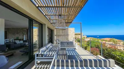 a group of chairs on a balcony with the ocean at Villa Caramontinu in Sainte-Lucie de Porto-Vecchio