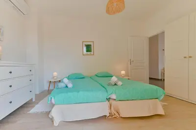 a white bedroom with a green bed and a dresser at Appartement refait à neuf, proche plage et centre ville- Ajaccio-Parc Berthaut in Ajaccio