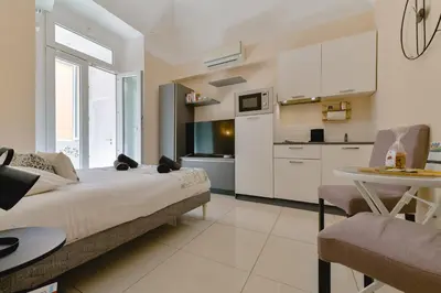 a bedroom with a bed and a table and a kitchen at Studio rénové Hyper Centre- Ajaccio in Ajaccio