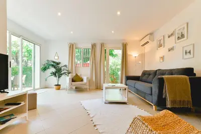 a living room with a couch and a table at Charmant Appartement - Jardinet Privé - 5 minutes des plages Sanguinaires - Ajaccio in Ajaccio