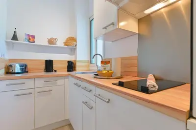 a kitchen with white cabinets and a wooden counter top at Charmant Appartement - Jardinet Privé - 5 minutes des plages Sanguinaires - Ajaccio in Ajaccio
