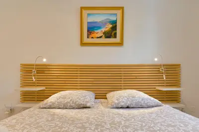 a bed with two pillows and a picture on the wall at Charmant Appartement - Jardinet Privé - 5 minutes des plages Sanguinaires - Ajaccio in Ajaccio