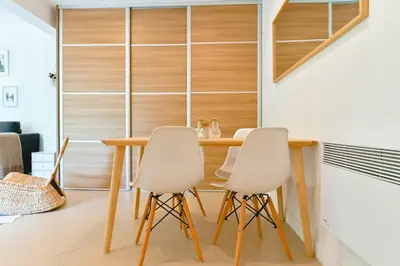 a dining room with a wooden table and white chairs at Charmant Appartement - Jardinet Privé - 5 minutes des plages Sanguinaires - Ajaccio in Ajaccio