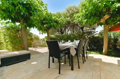 a dining table and chairs sitting under trees at Charmant Appartement - Jardinet Privé - 5 minutes des plages Sanguinaires - Ajaccio in Ajaccio