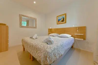 a bedroom with a bed and a mirror on the wall at Charmant Appartement - Jardinet Privé - 5 minutes des plages Sanguinaires - Ajaccio in Ajaccio
