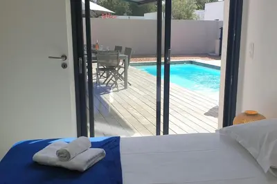 a bedroom with two towels on a bed next to a swimming pool at Villa Rossa 6 pers dans résidence avec piscine chauffée privée in Lecci