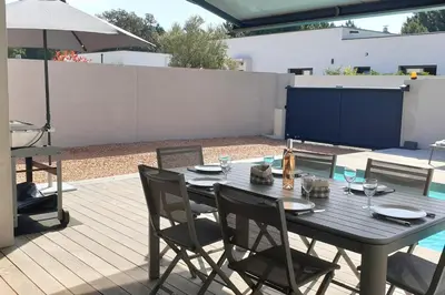 a wooden table with chairs and an umbrella on a patio at Villa Rossa 6 pers dans résidence avec piscine chauffée privée in Lecci