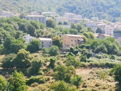 a small town on a hill with trees and houses at Maison de village avec jardin privatif in Zicavo