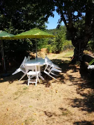 a table and chairs with a green umbrella at Maison de village avec jardin privatif in Zicavo