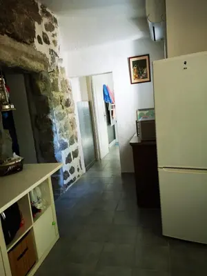 a kitchen with a refrigerator and a stone wall at Maison de village avec jardin privatif in Zicavo