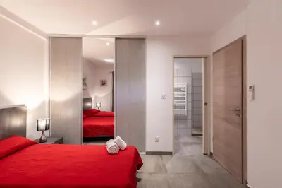 a bedroom with a red bed and a mirror at Les Arcades de Cala Rossa in Lecci